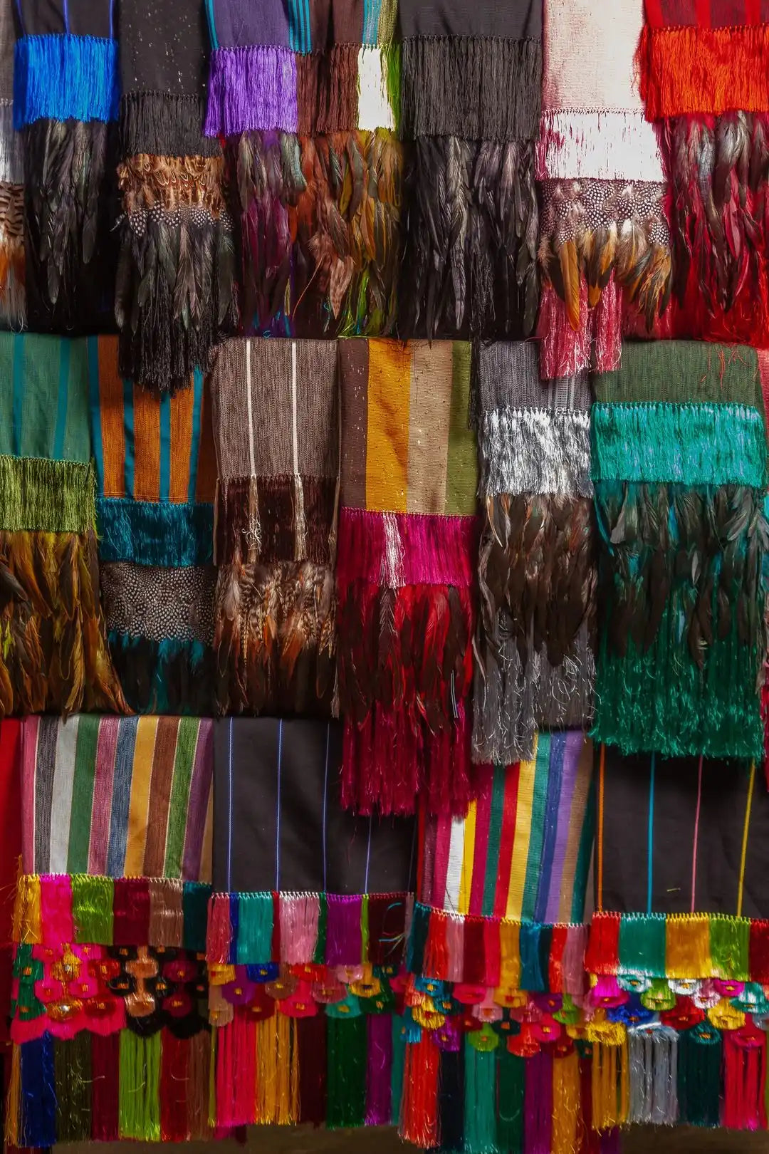 A vibrant display of colorful, fringed textiles and scarves.