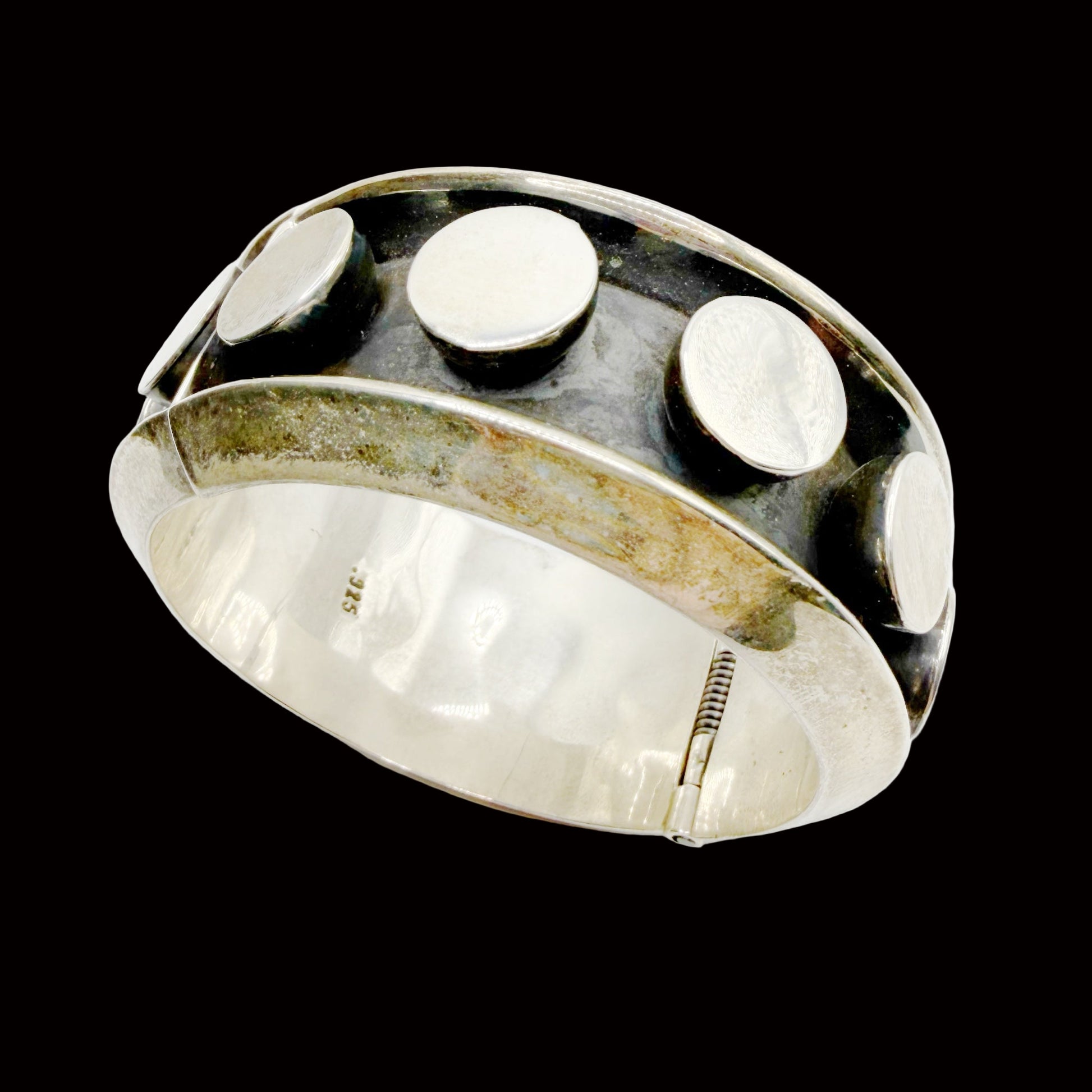 Silver bracelet with three circular stones on a white background