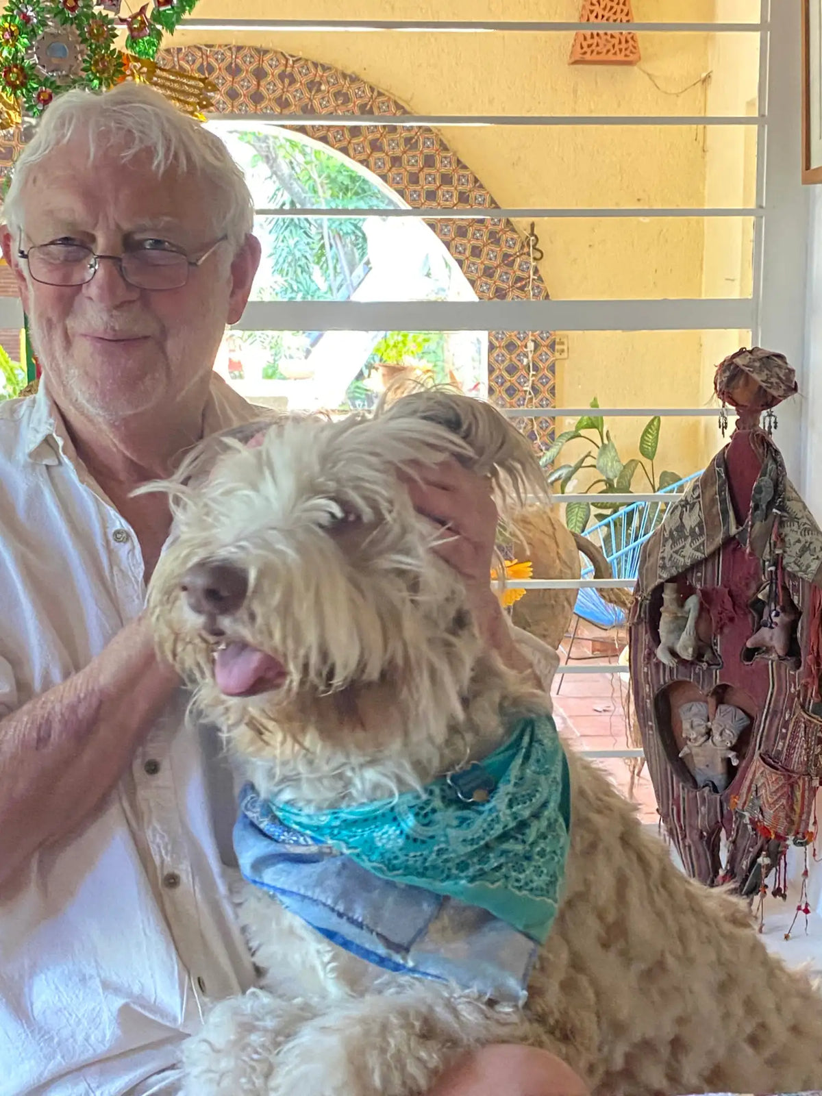 A fluffy, light tan dog wearing a teal lace bandana.