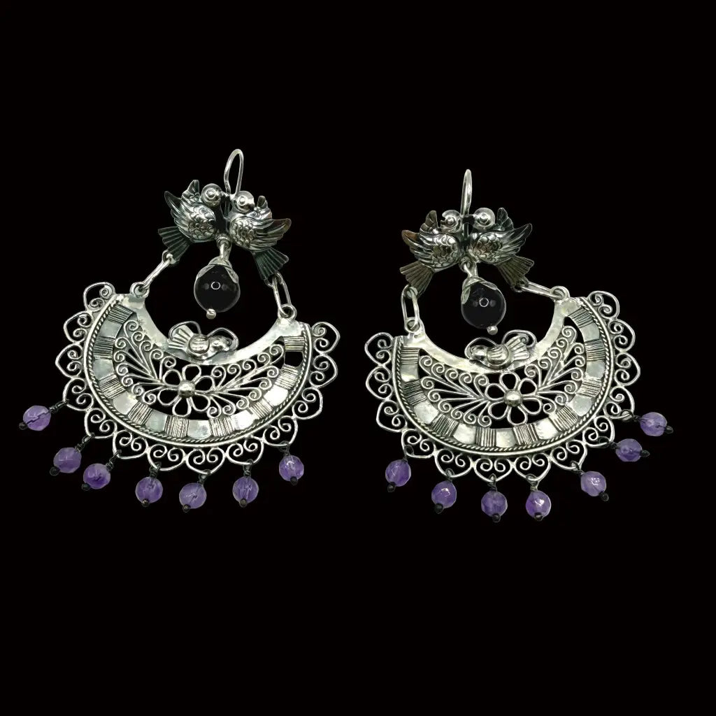 Close-up of paired silver palomas cradling amethyst stone on Mazahua handmade wedding earrings