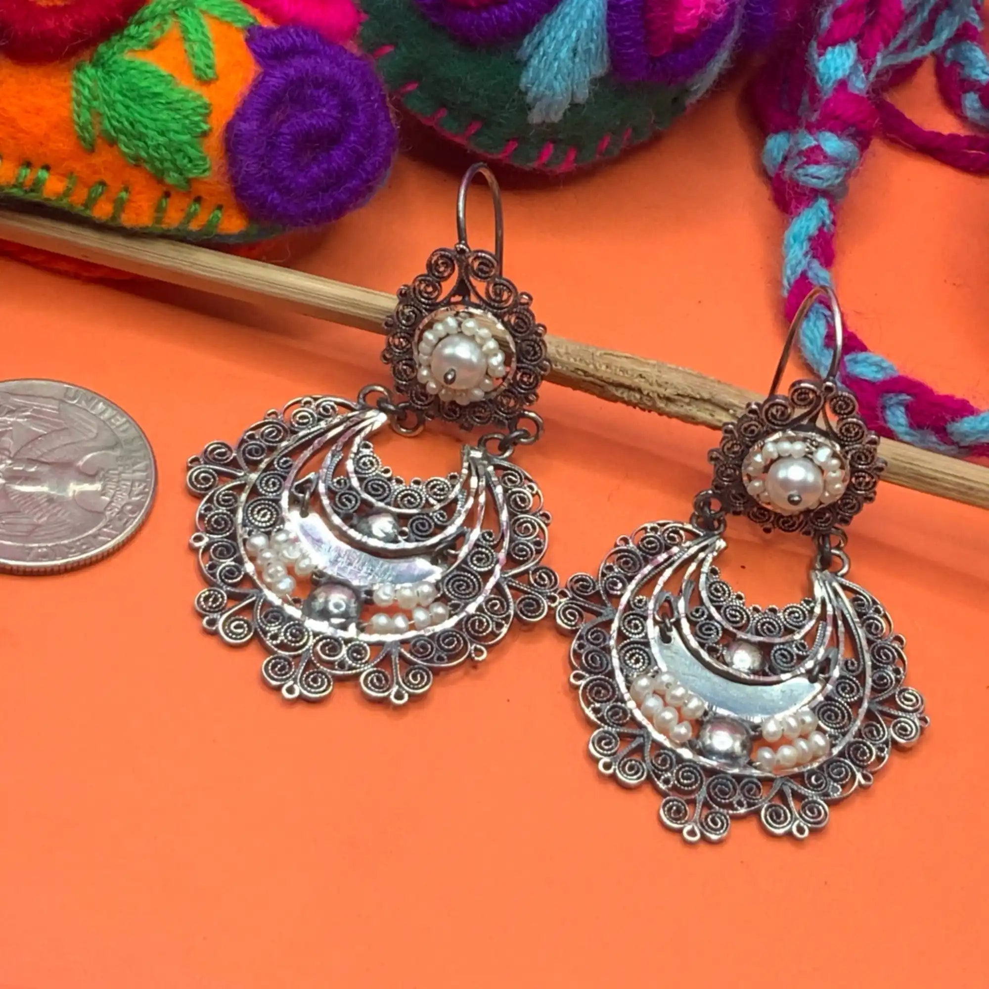A pair of ornate silver earrings with filigree work and pearl accents.