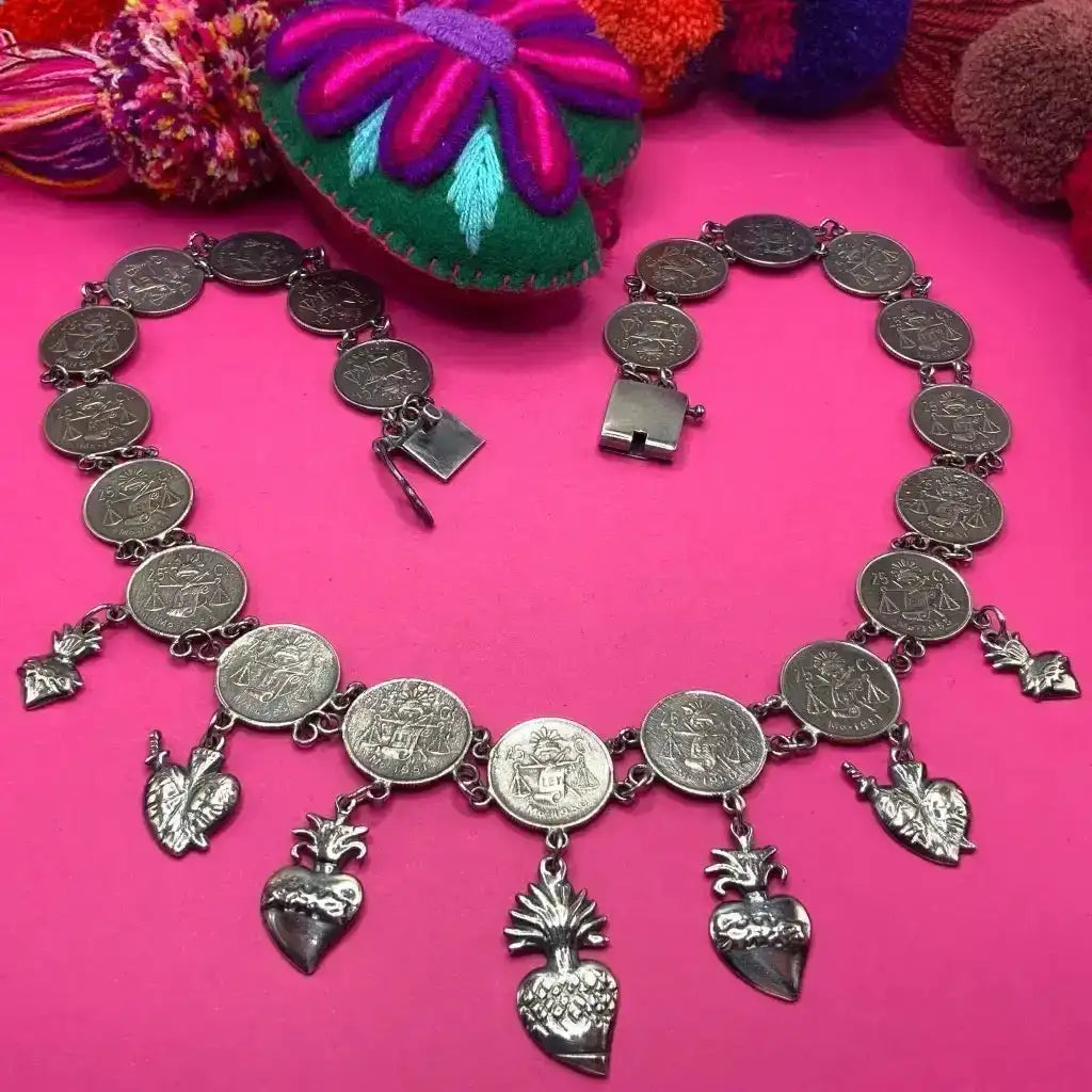 Silver coin necklace with heart pendants and leaf charms.