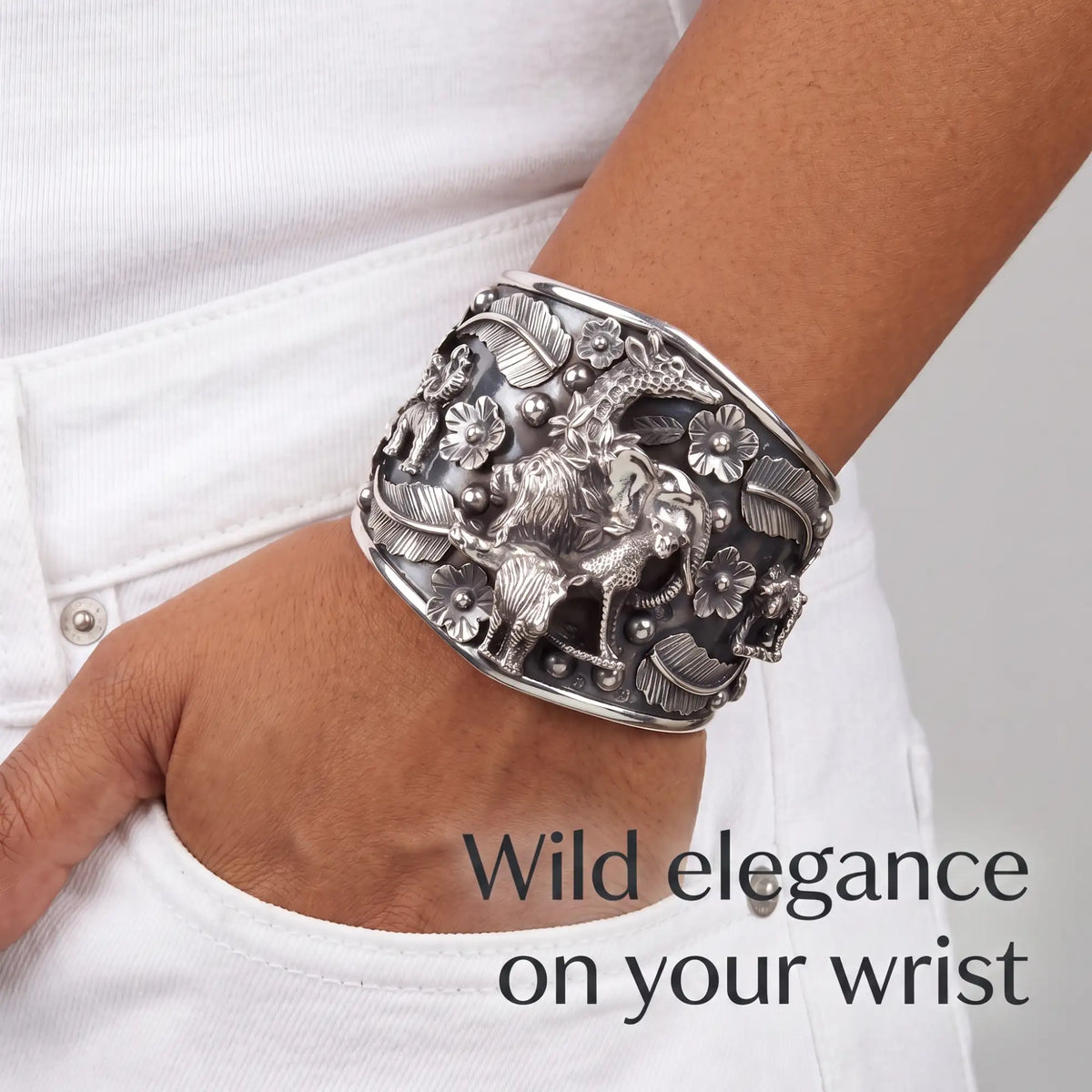 Silver cuff bracelet featuring intricate wildlife and floral designs with detailed embossed animals and leaf patterns.